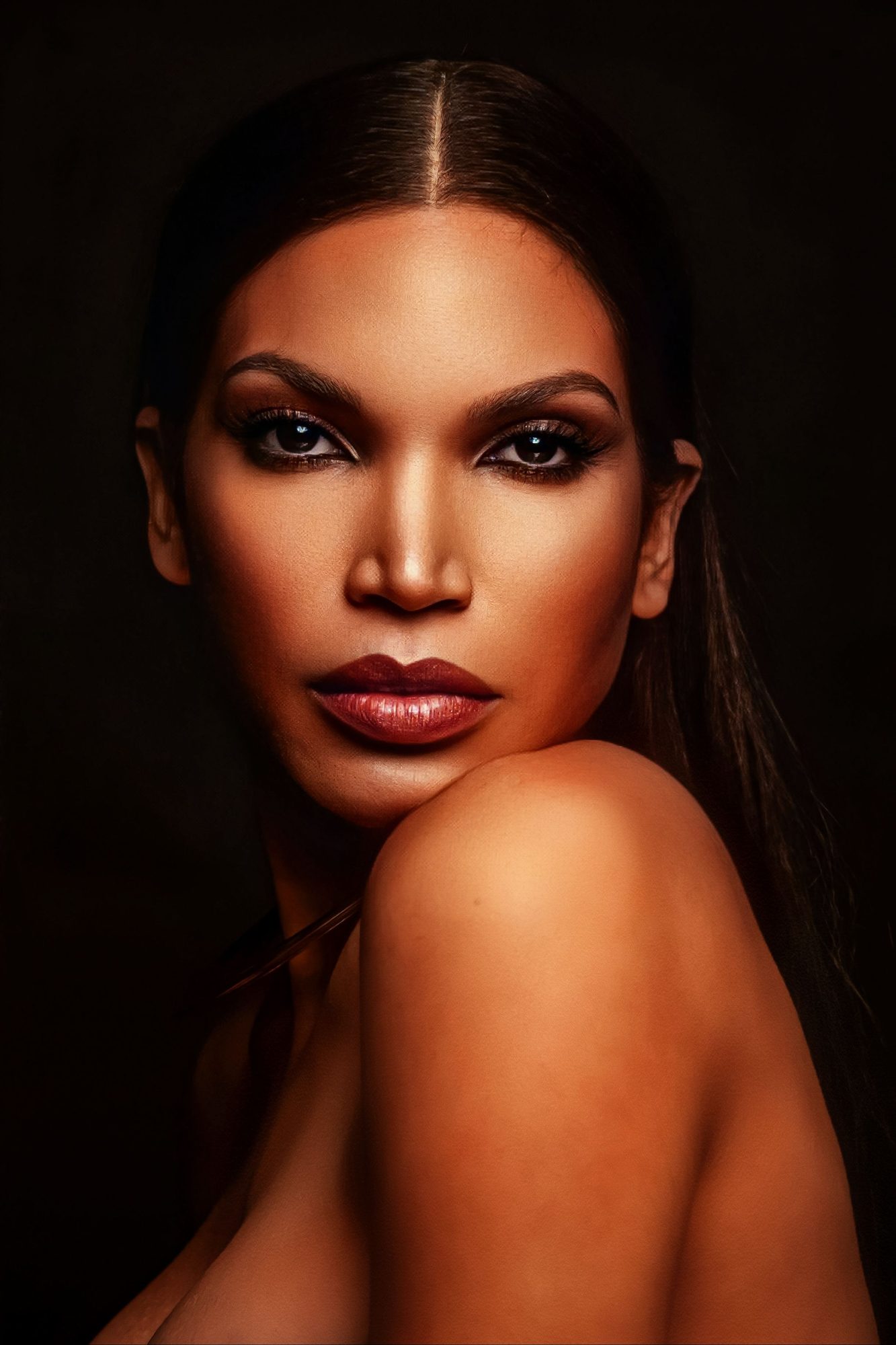 Beauty portrait of a woman looking over a bare shoulder on a dark ground