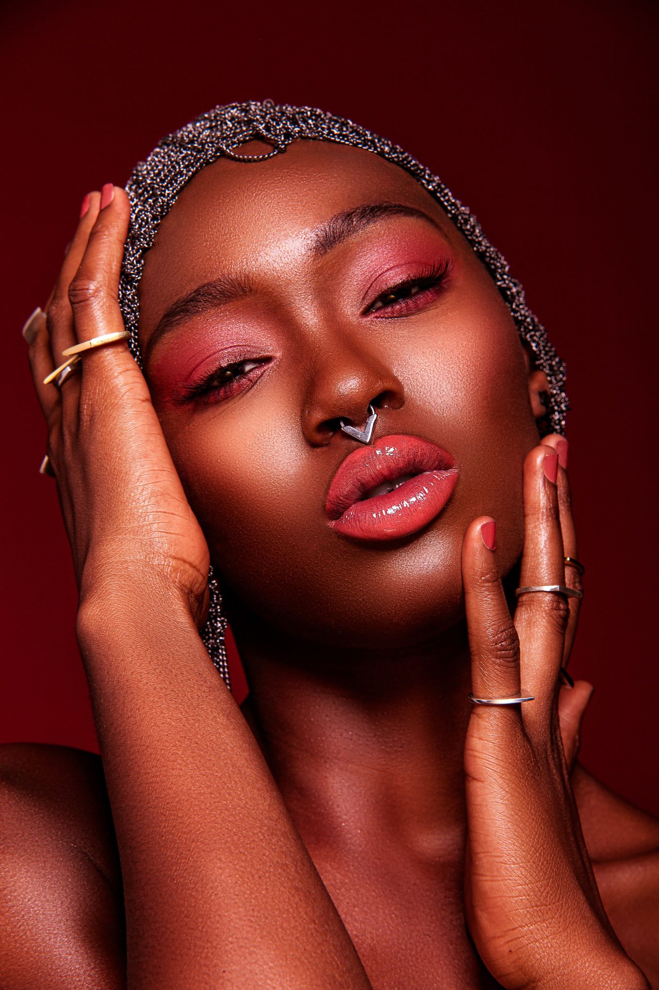 Beauty portrait with a beaded headpiece and rings on a red ground