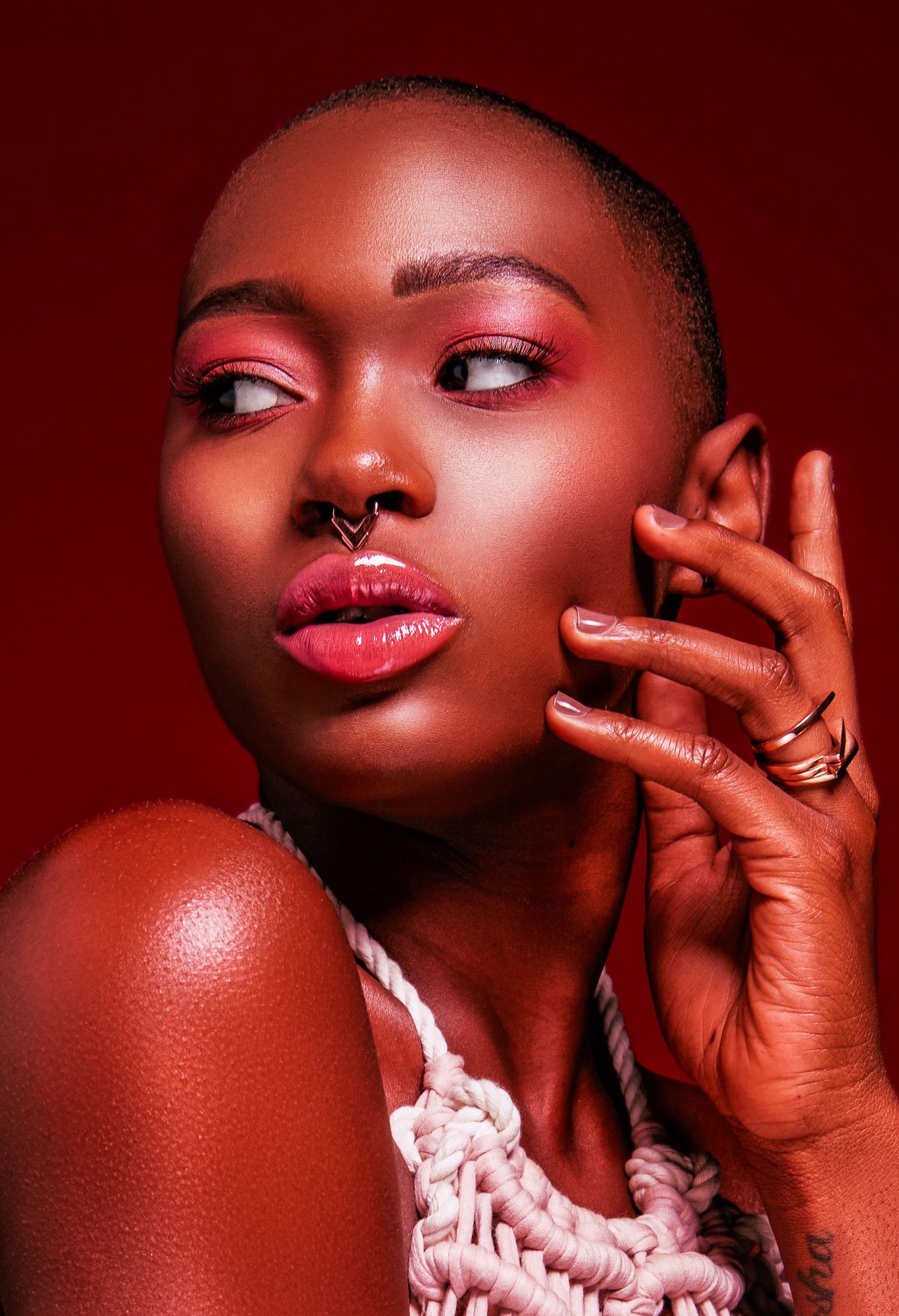 Beauty portrait with pink makeup and a macrame top on a red ground