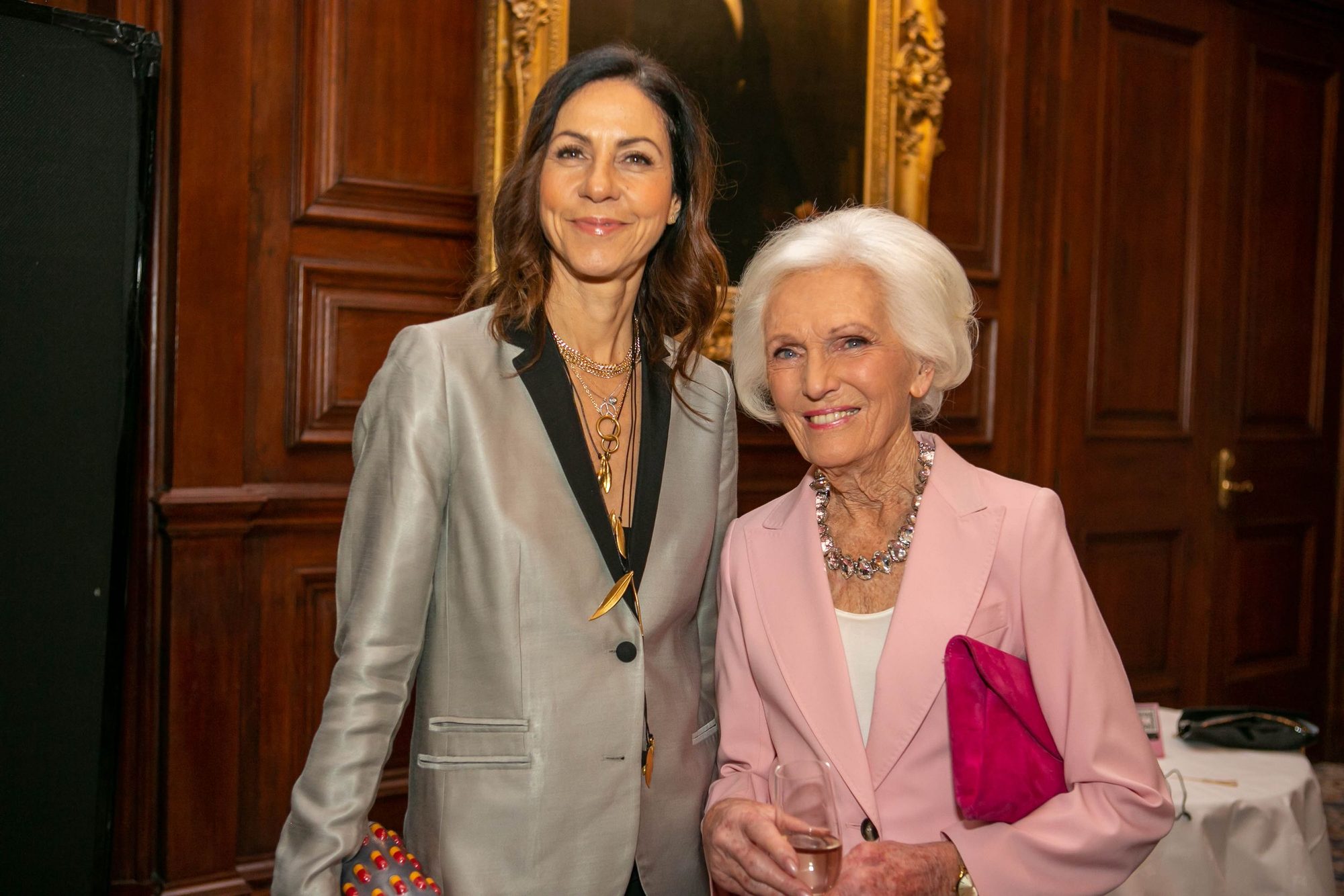 Two women smiling at a dinner in a wood panelled room