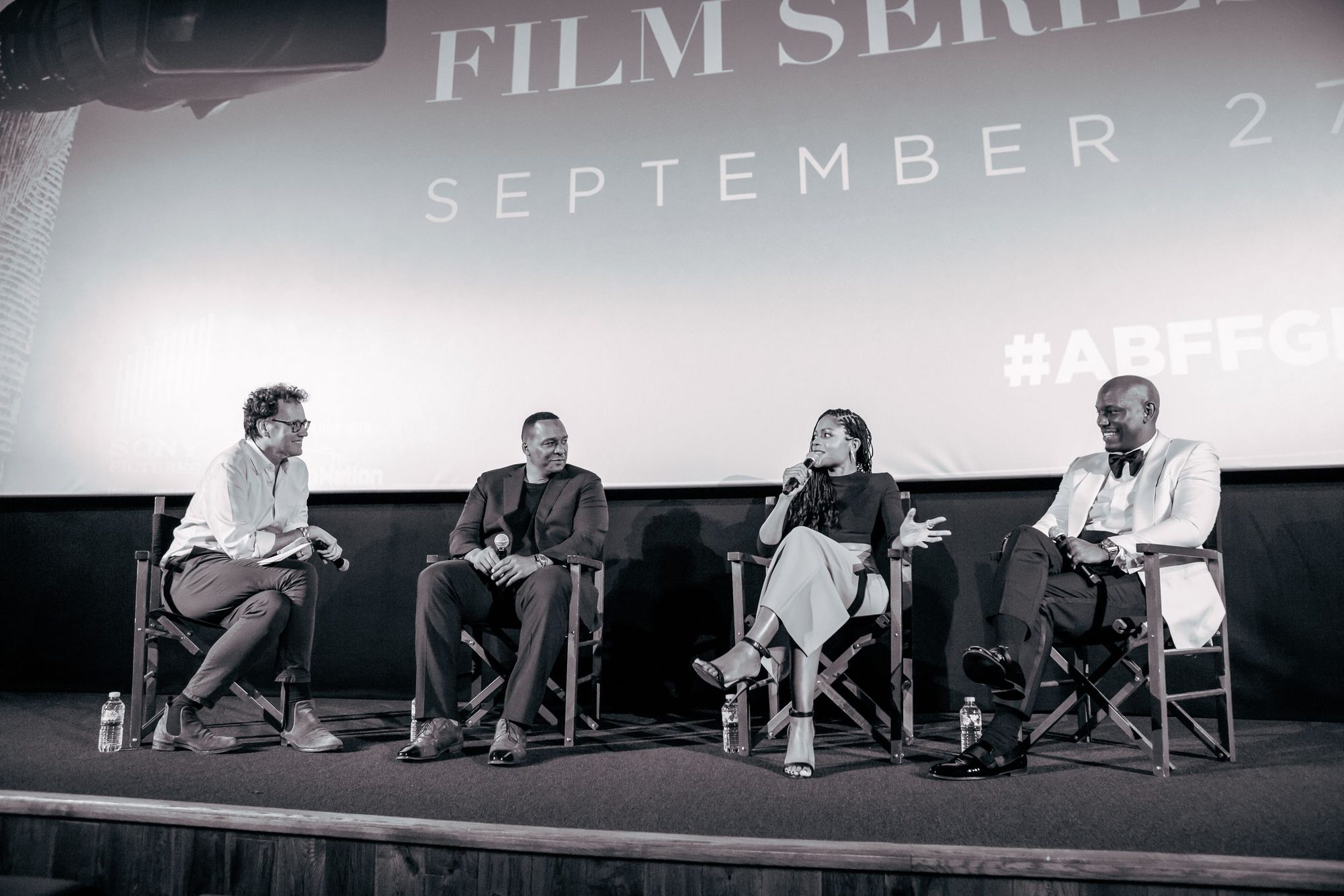 Black and white photo of a film panel on stage under the screen
