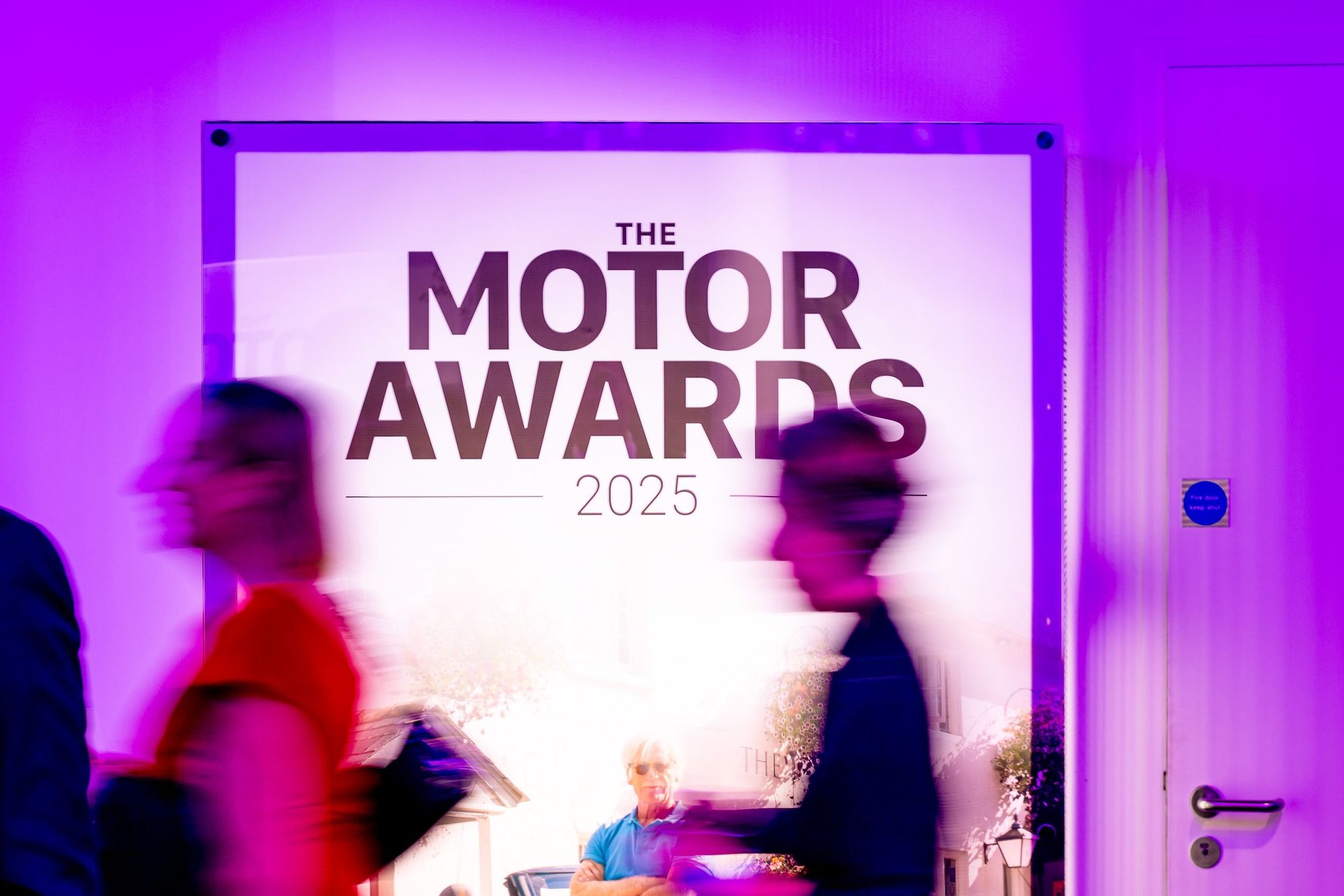 Guests passing the Motor Awards sign lit in purple