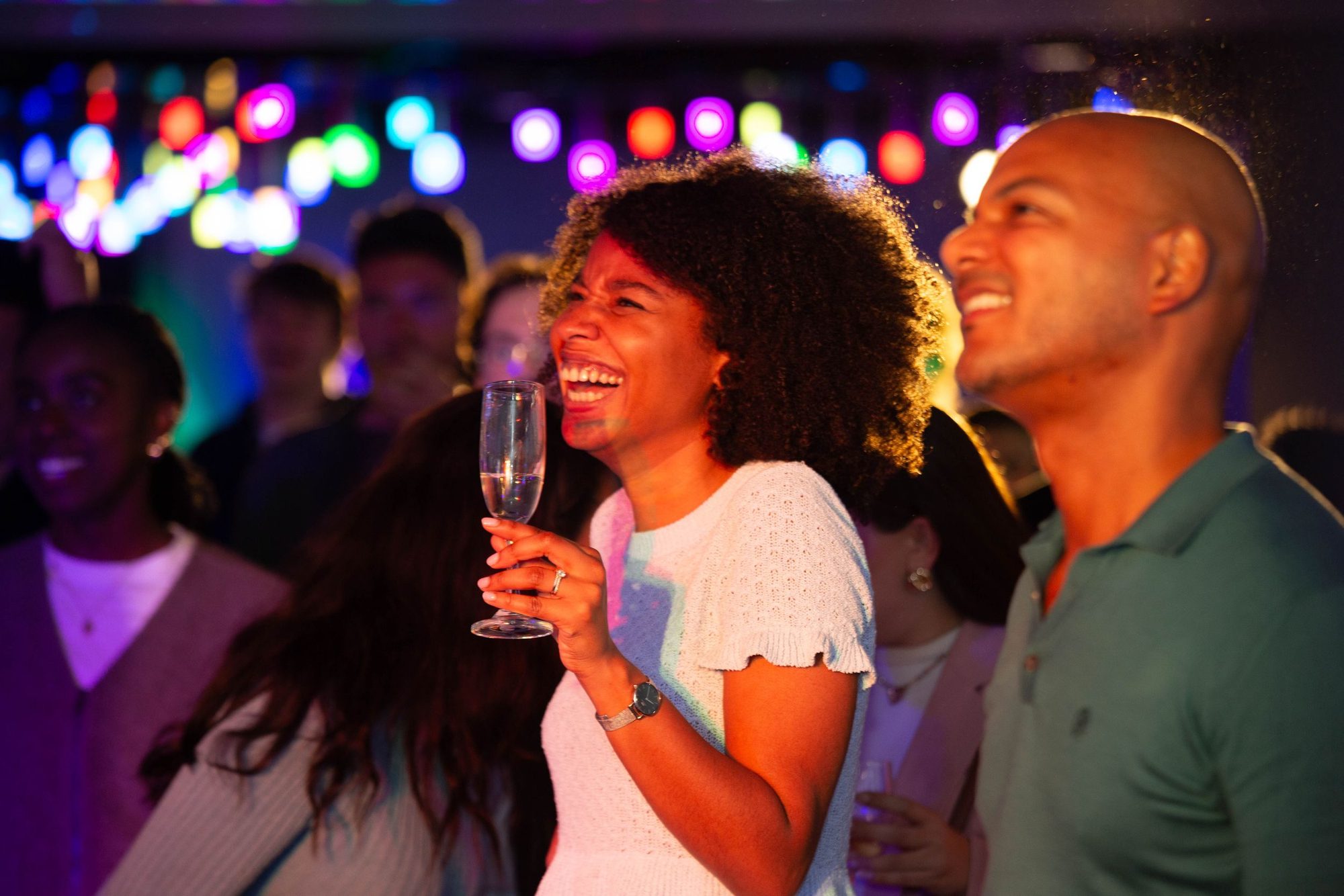 Party guests laughing under coloured lights