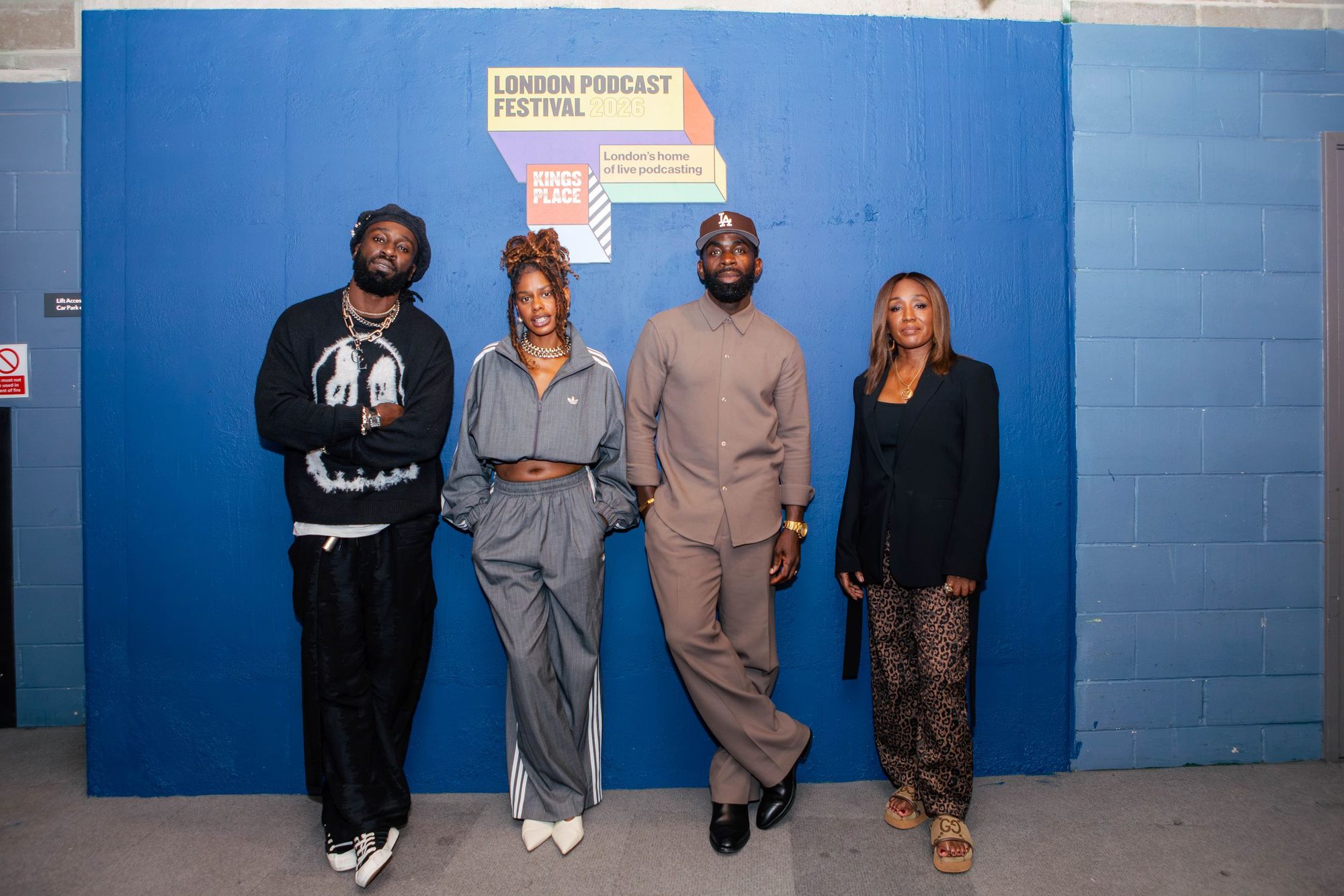 Four people standing against a blue wall at a podcast festival