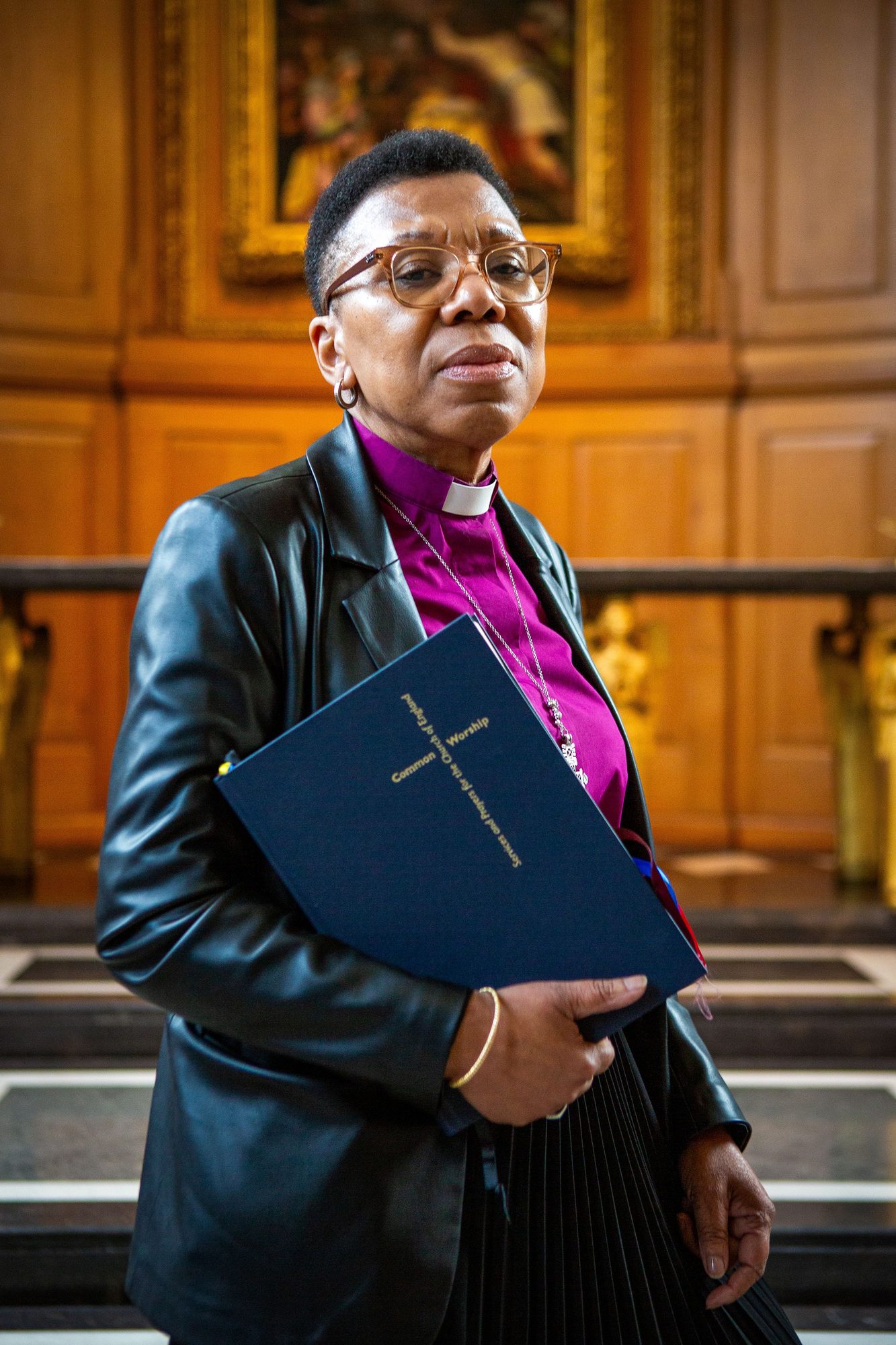 Bishop in a purple clerical shirt holding a bible inside a church