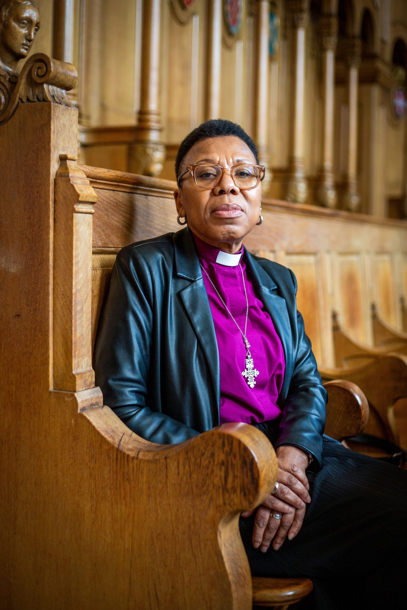 Bishop in a purple clerical shirt seated in a church pew