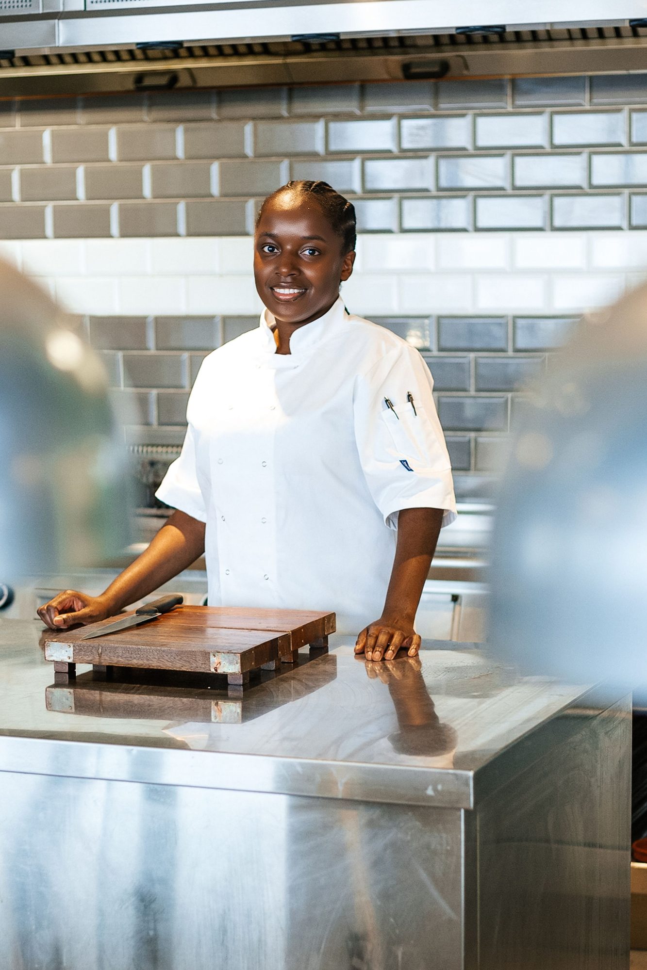 Chef in whites at a steel counter in a tiled kitchen