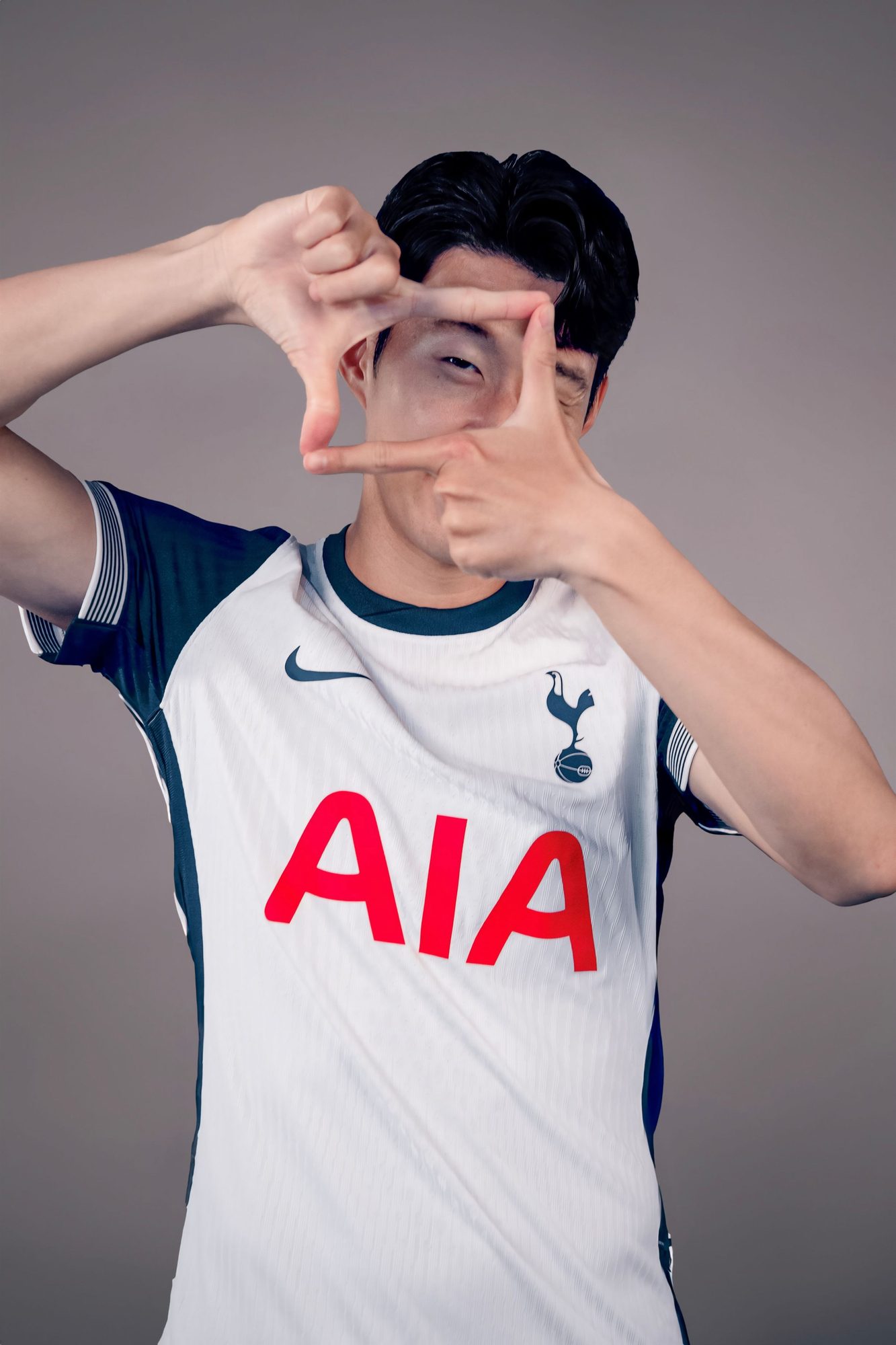 Footballer in a white kit framing his face with his hands
