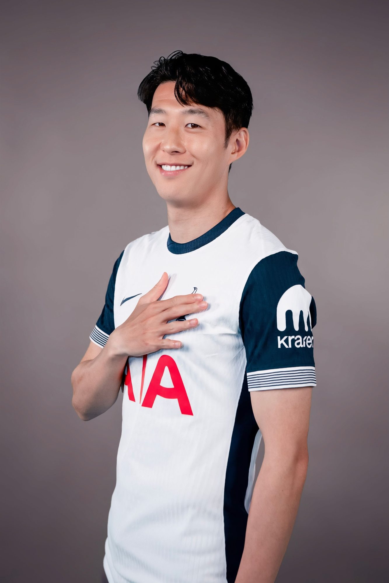 Footballer in a white kit with a hand on his chest