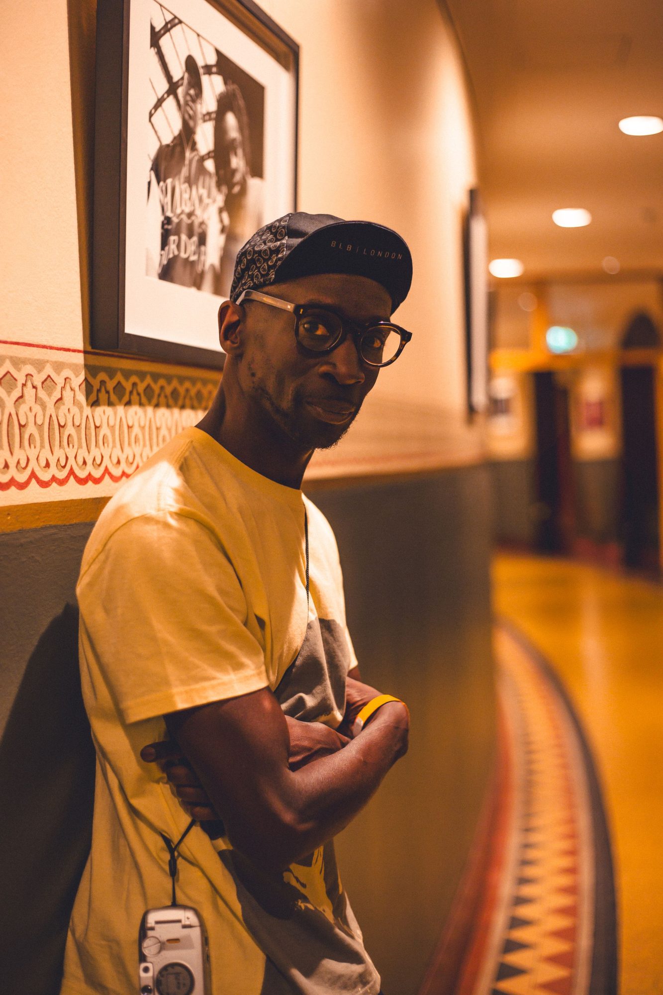 Man in a cap and yellow t-shirt in a warmly lit corridor