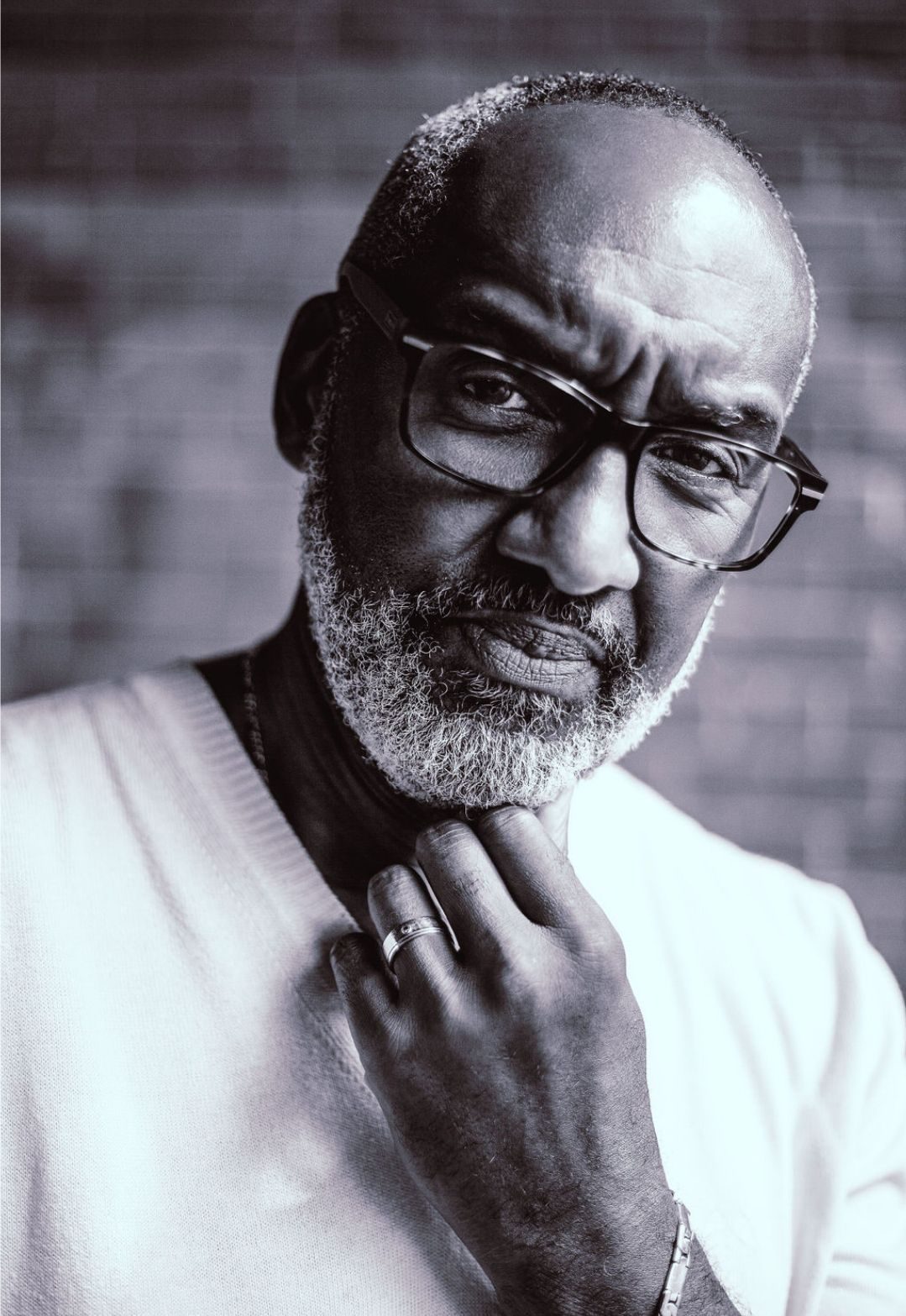 Black and white portrait of an older man in glasses, hand at his chin