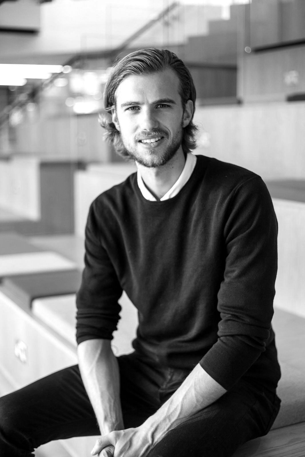 Black and white portrait of a young man seated in a dark jumper