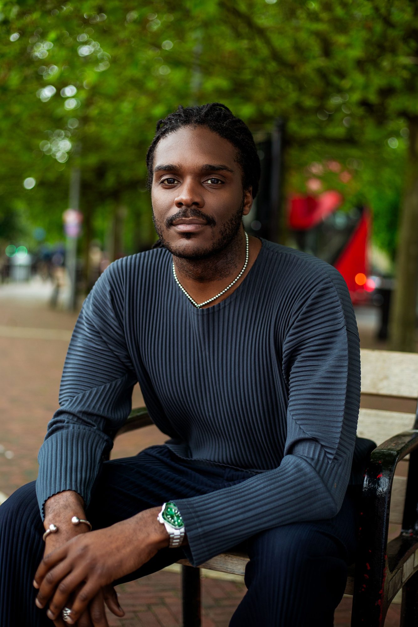 Man in a dark top seated in a green park
