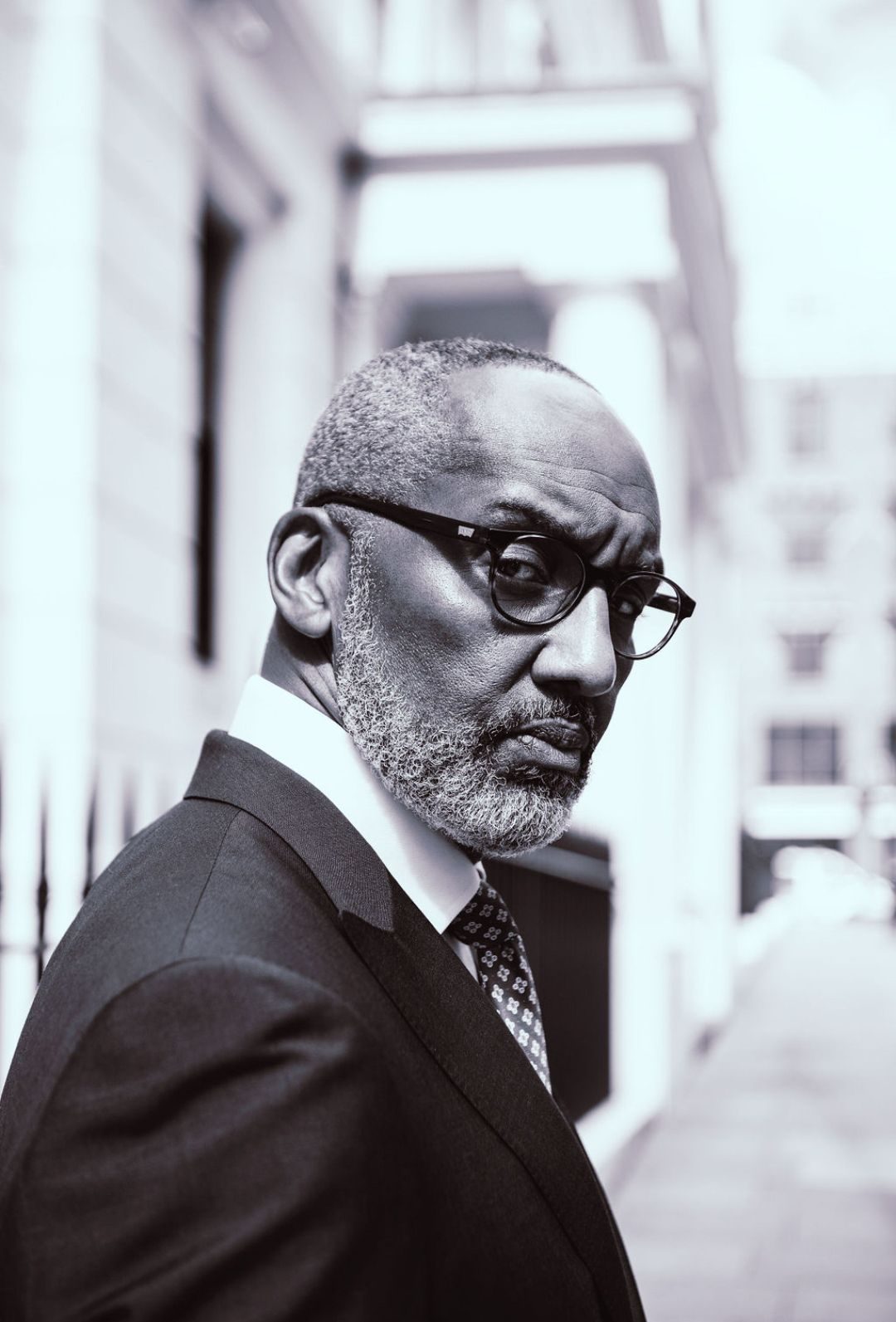 Older man in a dark suit and glasses on a city street