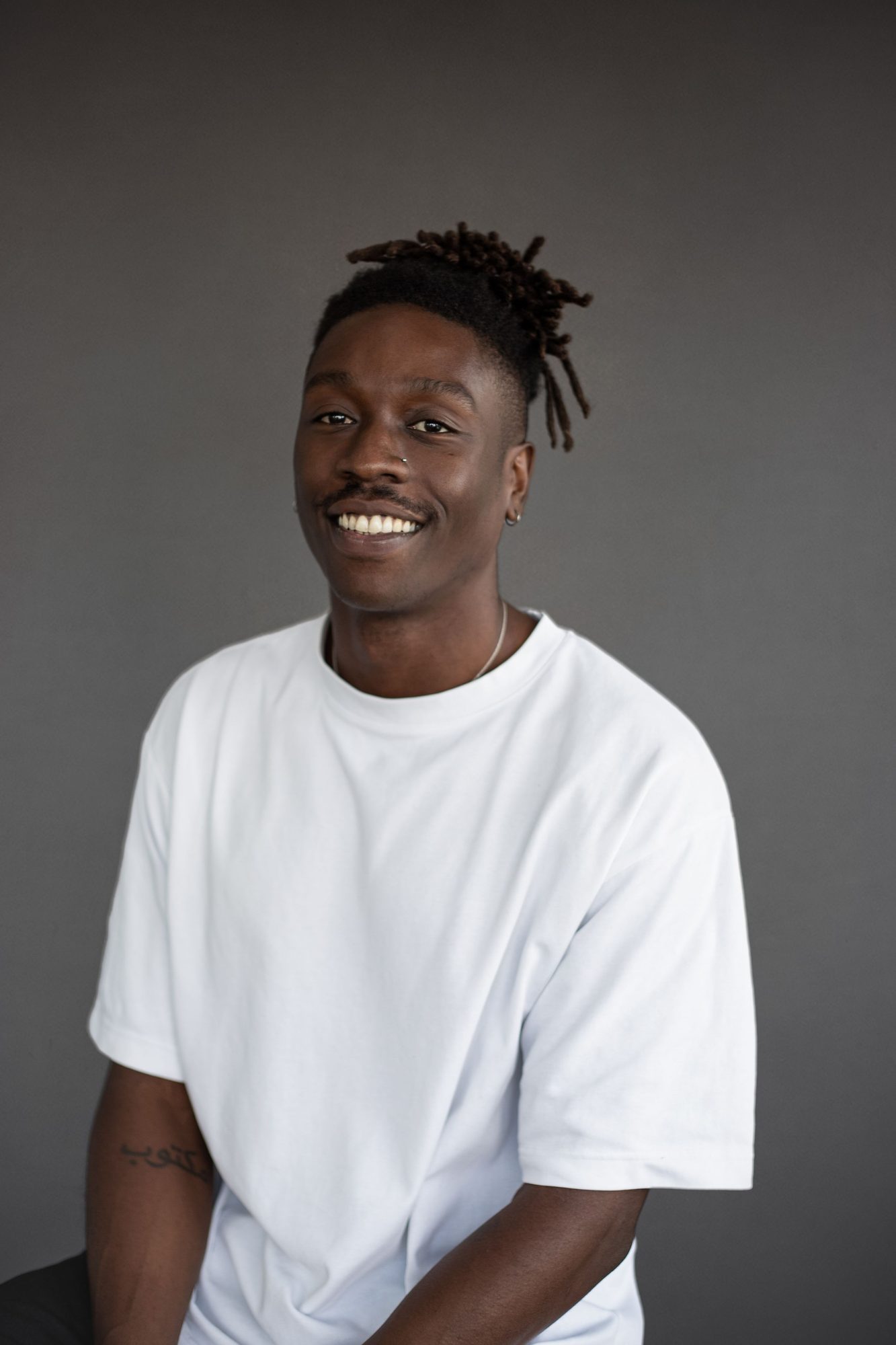 Smiling man in a white t-shirt against a grey backdrop
