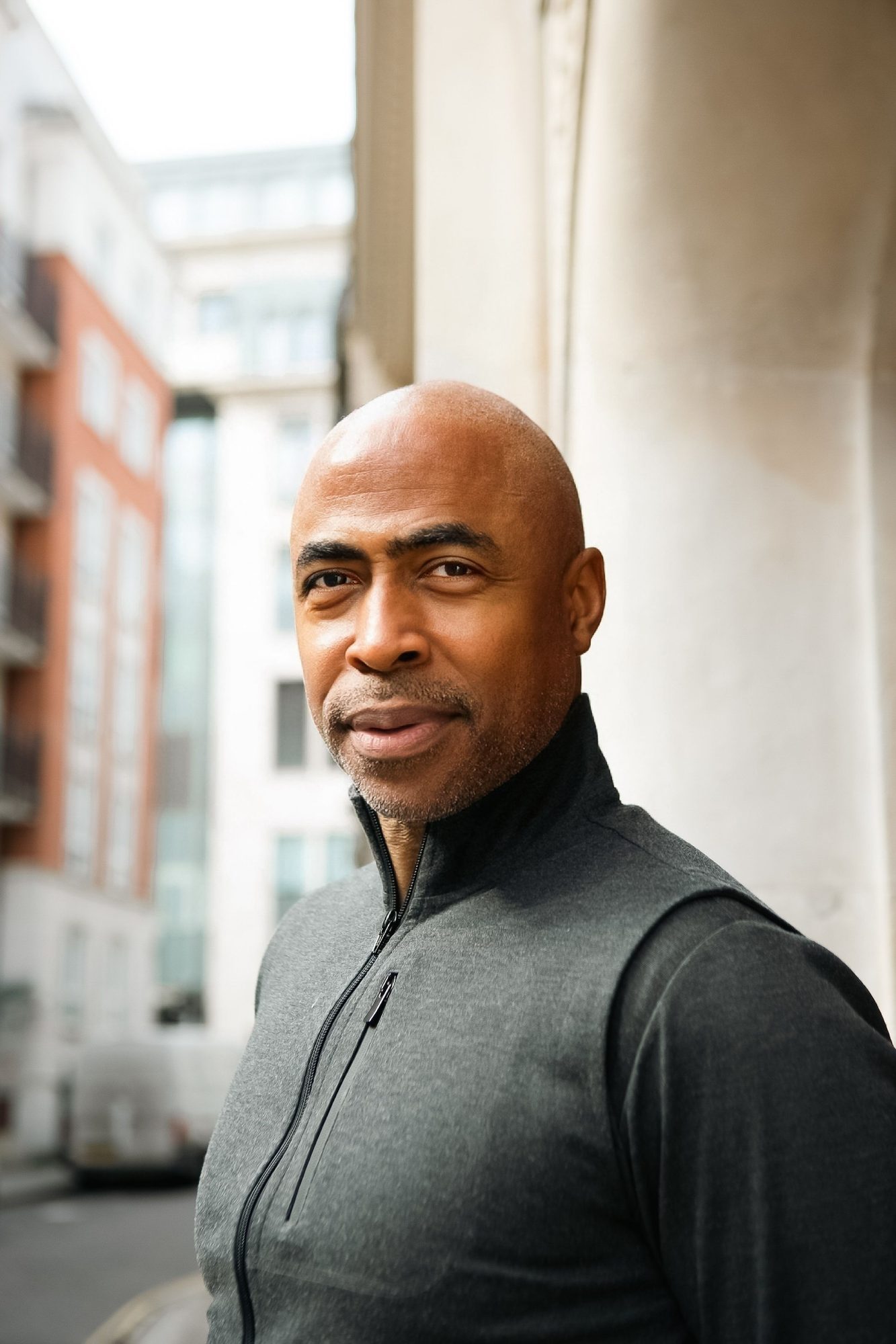 Man in a dark zip top in front of red brick buildings
