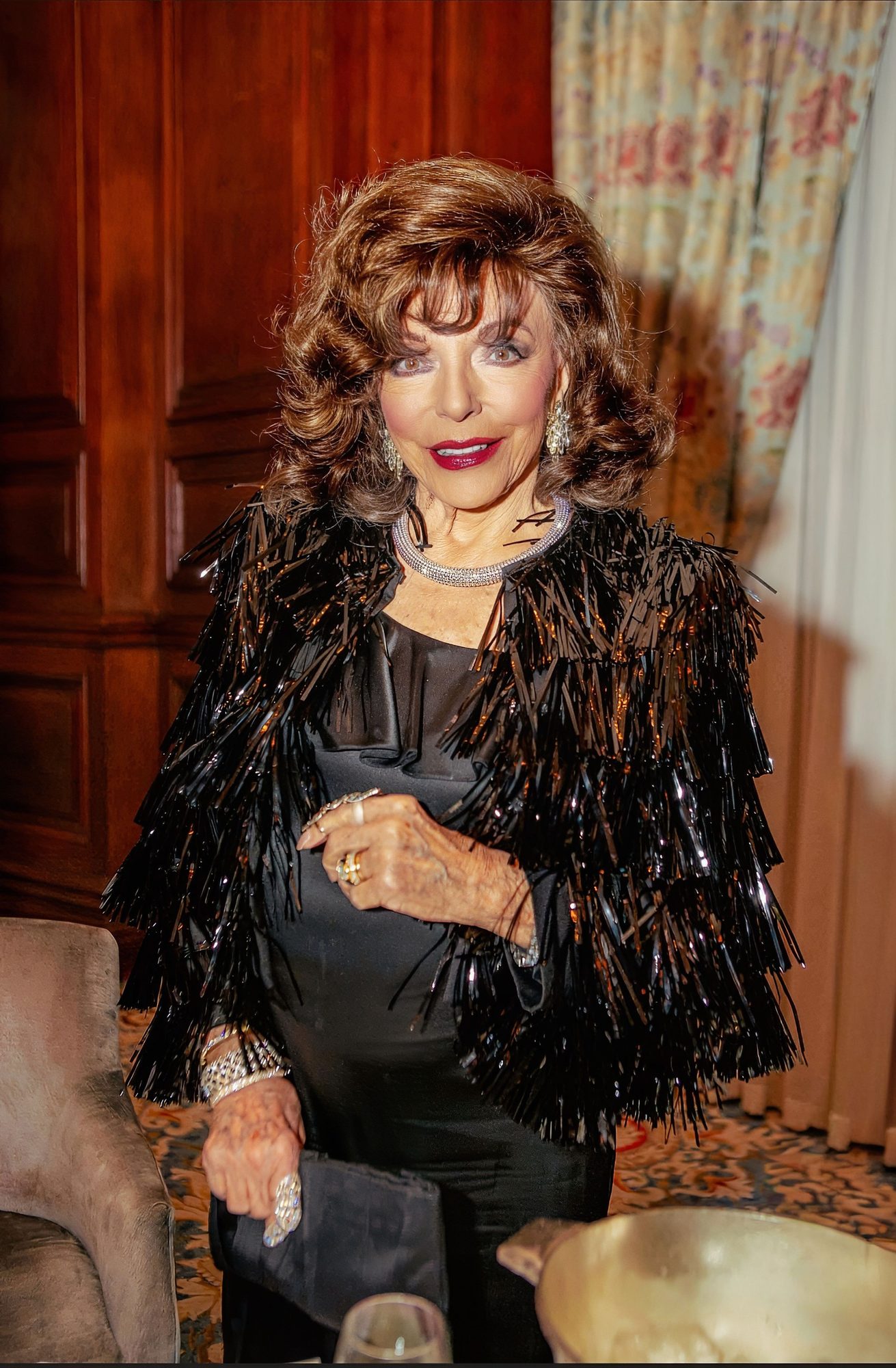 Woman in a black fringed jacket in an ornate hotel room