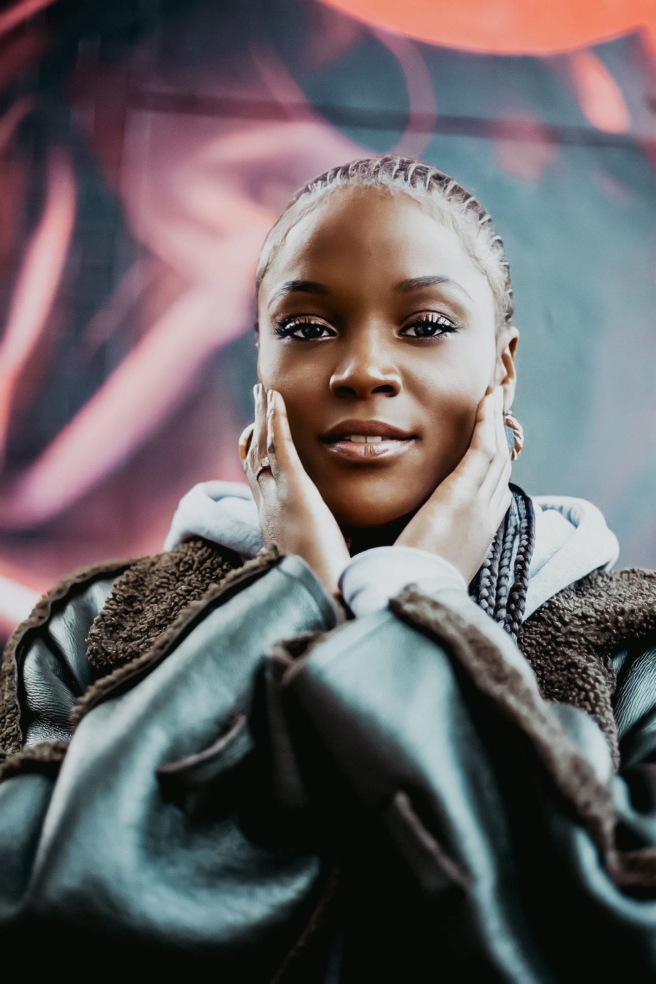 Woman with white braids, hands at her face, in a padded jacket