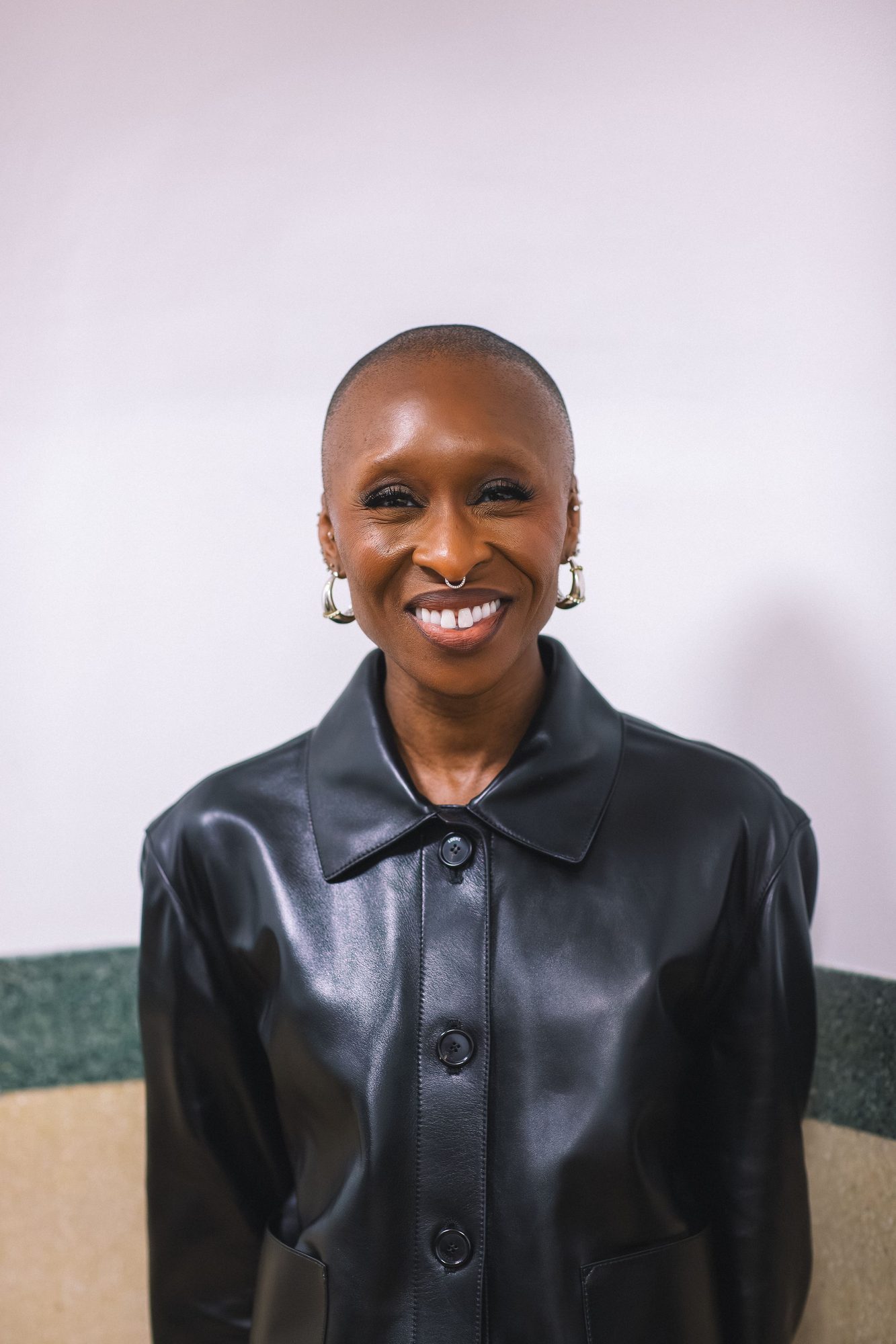Smiling woman in a black leather jacket against a pale backdrop