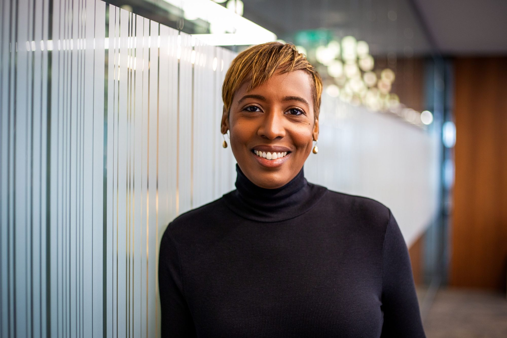 Smiling woman in a black polo neck in a bright office