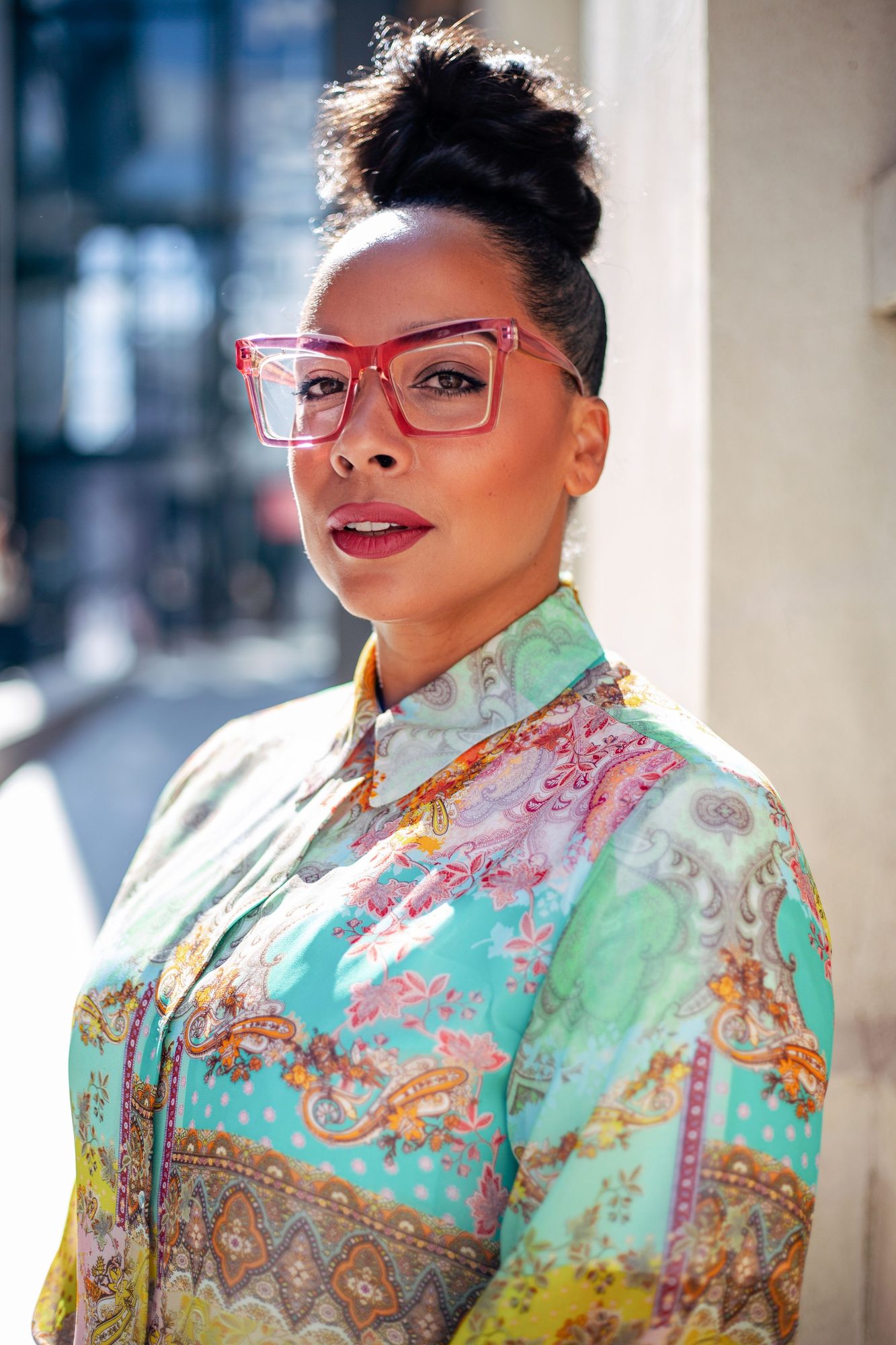 Woman with red glasses and a printed silk shirt in a city street