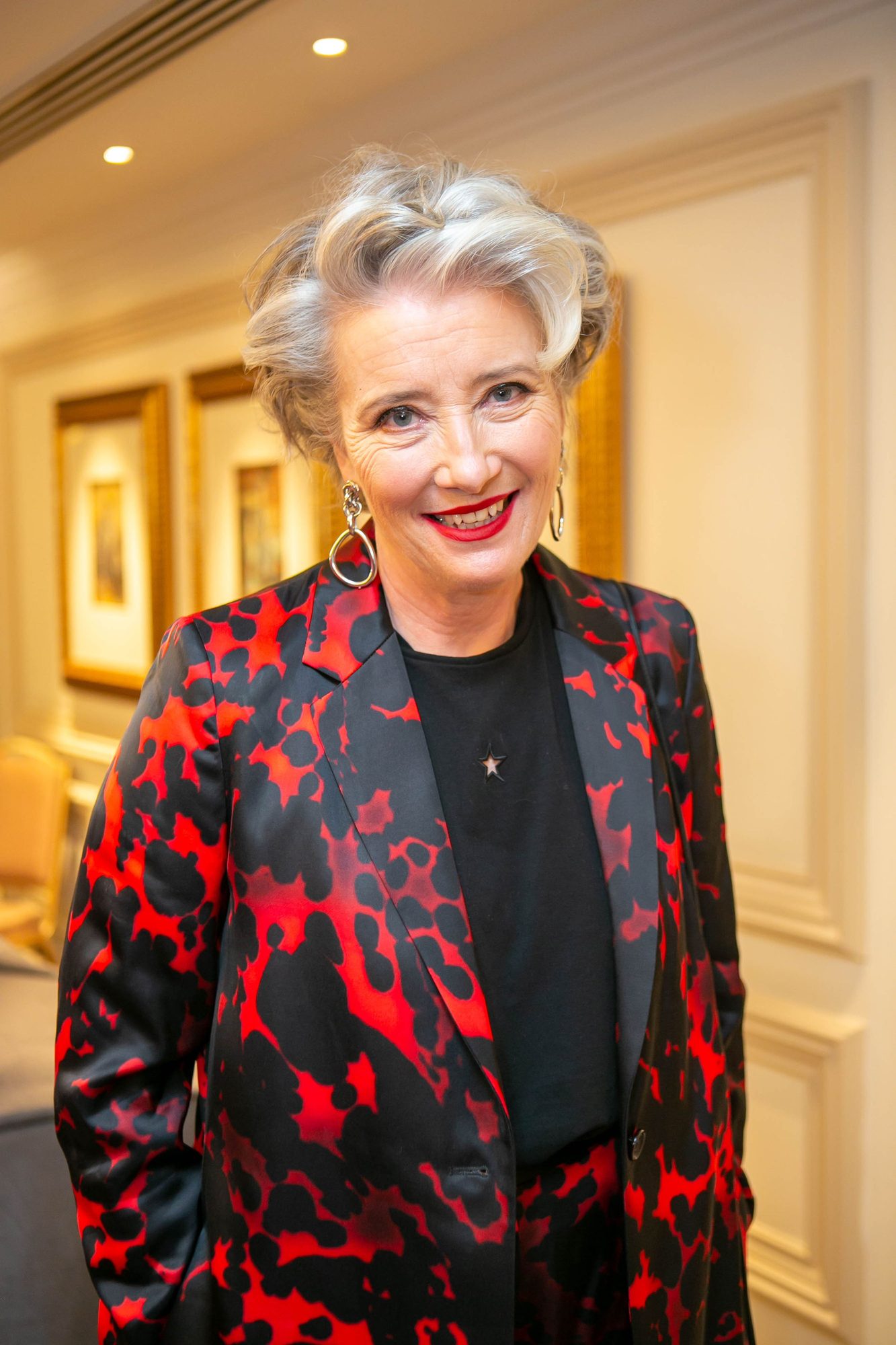 Woman with silver hair in a red and black jacket in a hotel