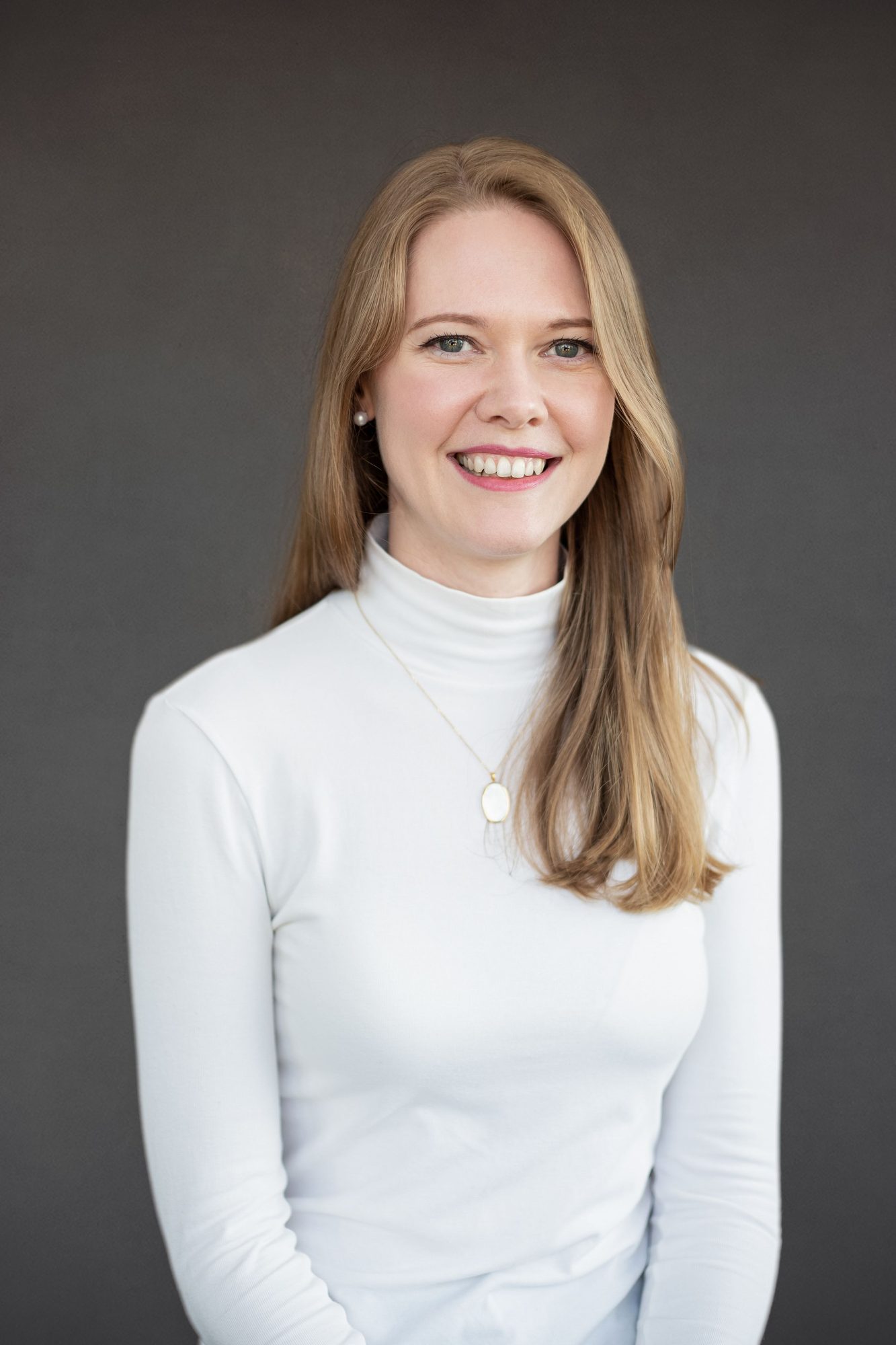 Woman in a white polo neck against a grey backdrop